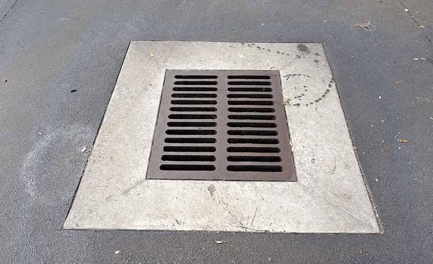 Parking lot drainage detail — a catch basin drain grate set flush into the asphalt to manage stormwater runoff