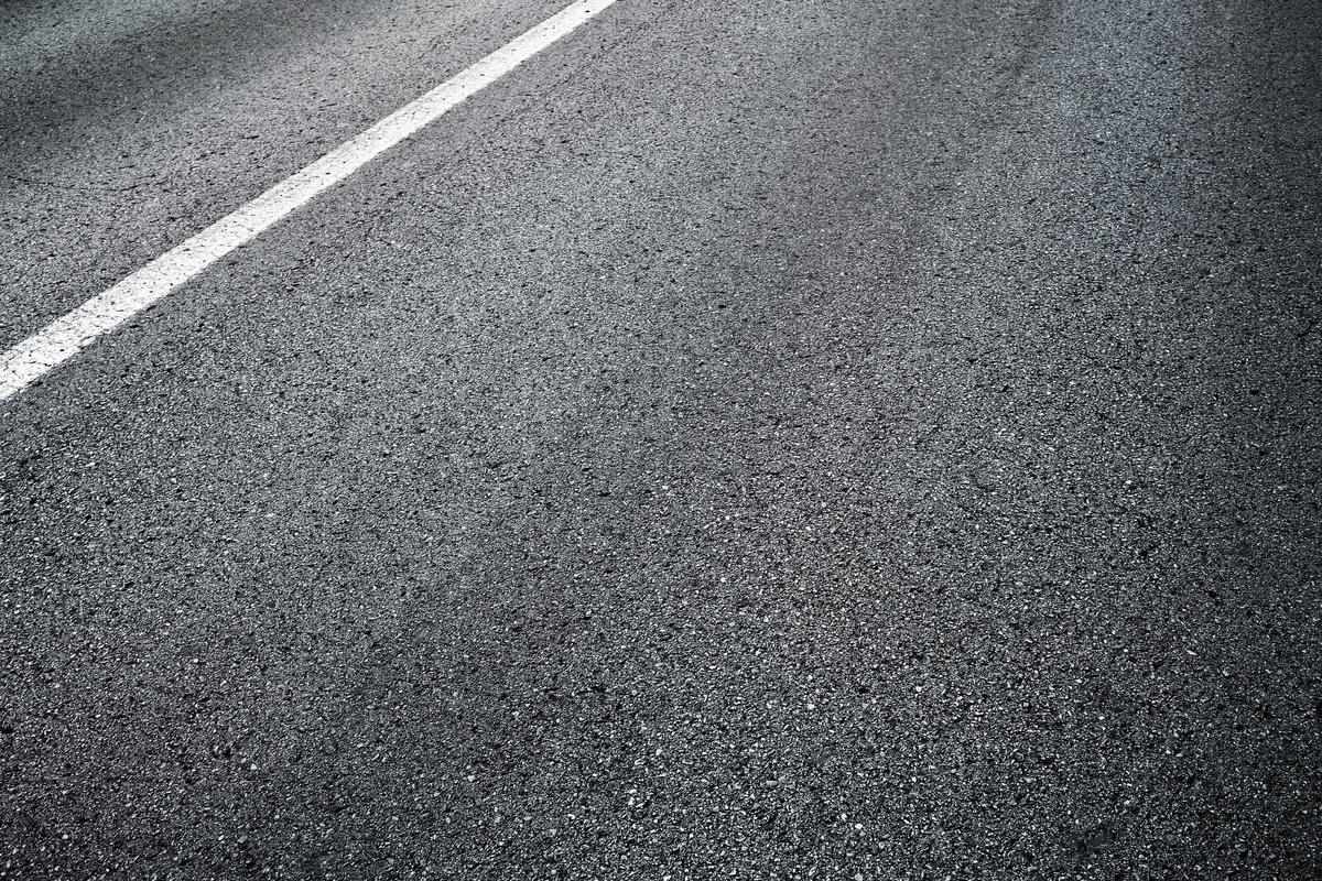 Pavement construction result — a close-up of a finished asphalt road surface with a painted lane line