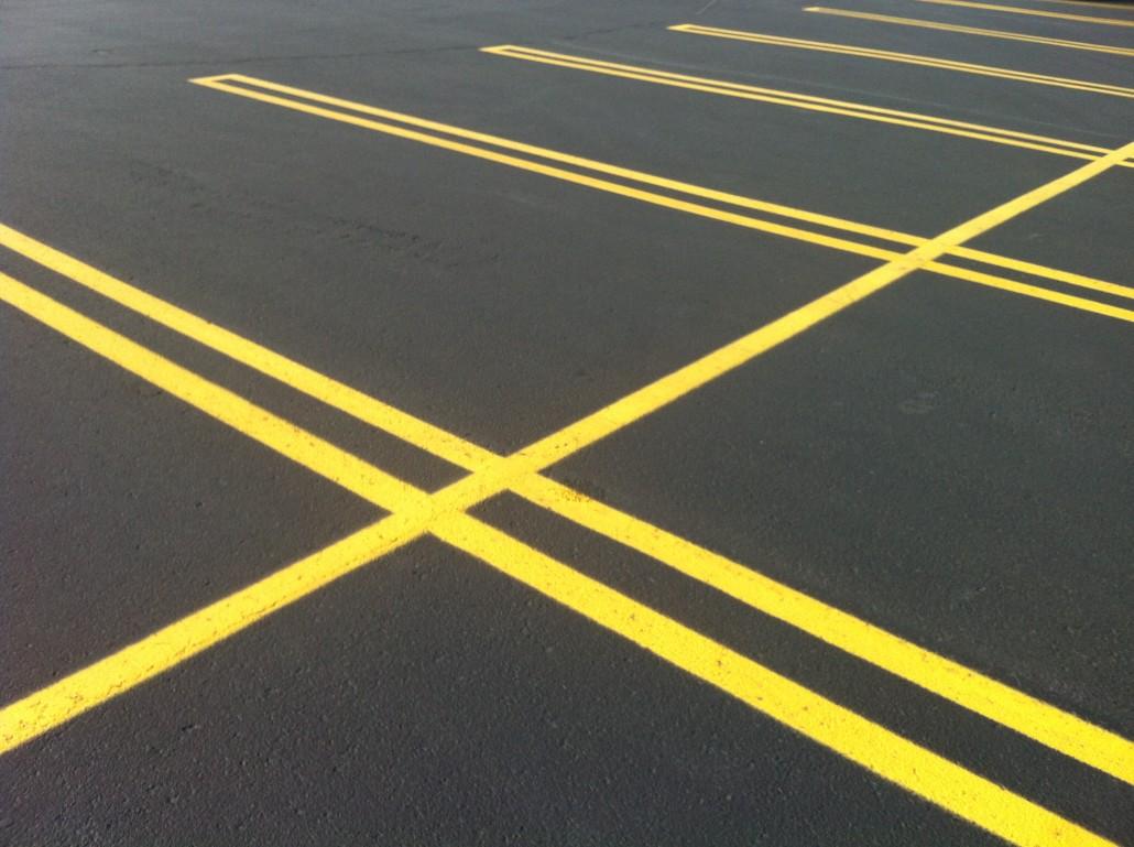 Pavement marking result — crisp double yellow striping lines freshly painted in a commercial parking lot