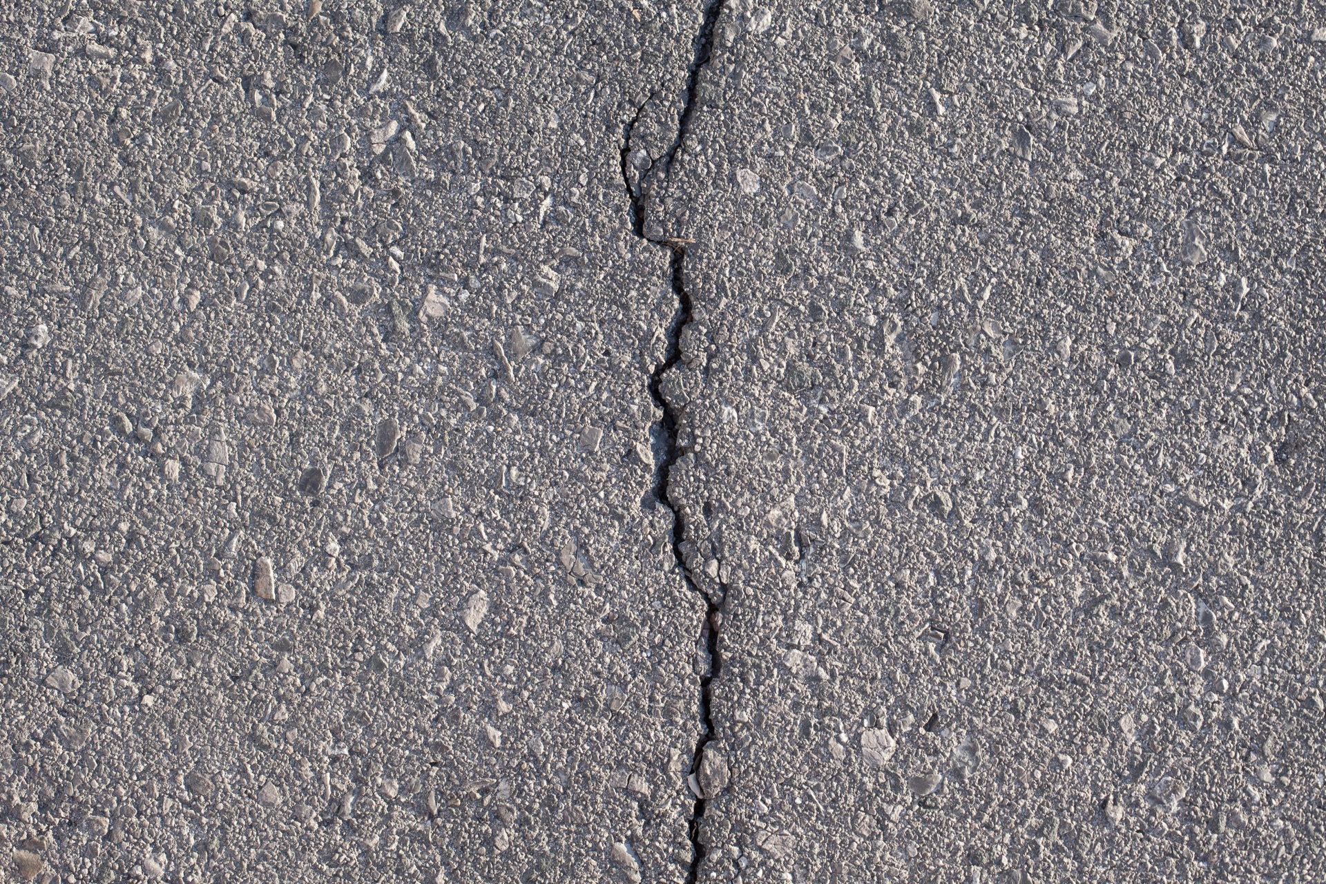 Close-up crack running through blacktop, a sign the surface has reached the end of its life
